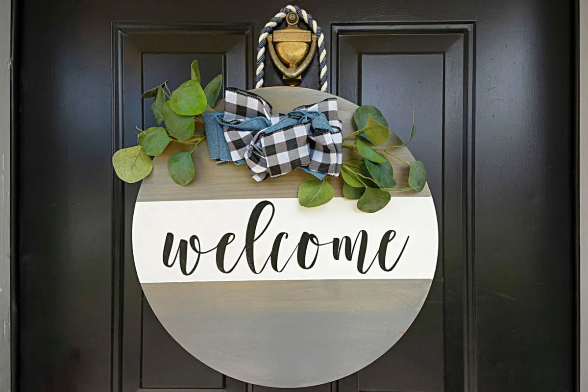 A warm and inviting entryway features a welcome sign adorned with greenery and a decorative bow, signaling a pleasant arrival experience. The scene suggests a space where guests are greeted with care and comfort.